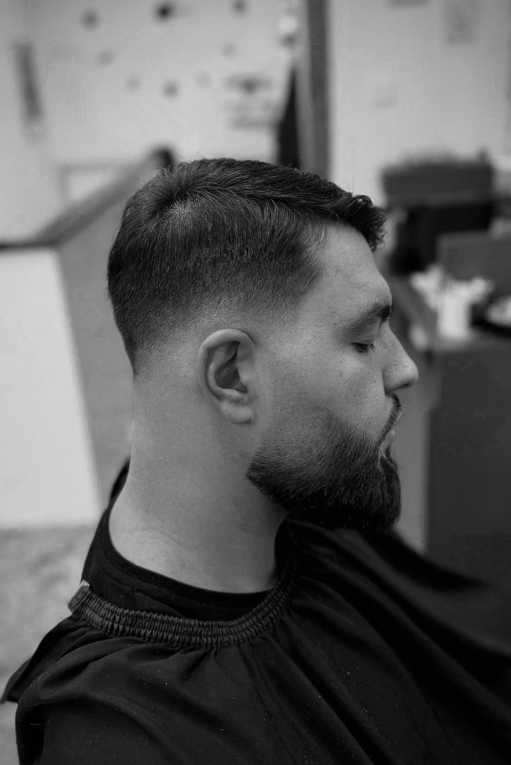 Herrenhaarschnitt mit Fade und gepflegtem Bart in Schwarzweiß